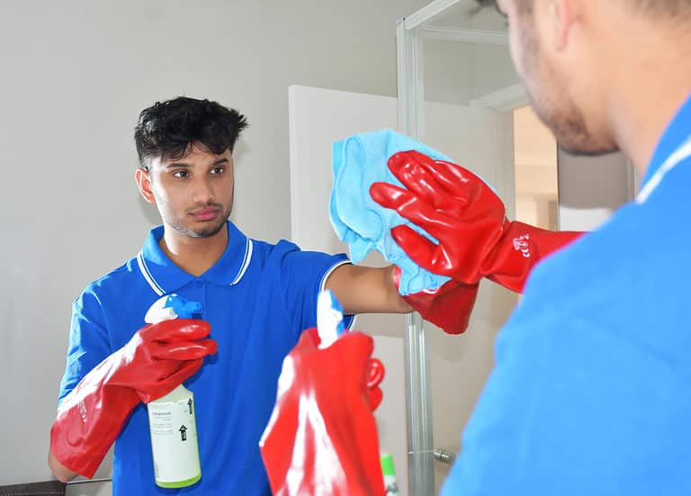 United Home Services Cleaner polishing a mirror clean